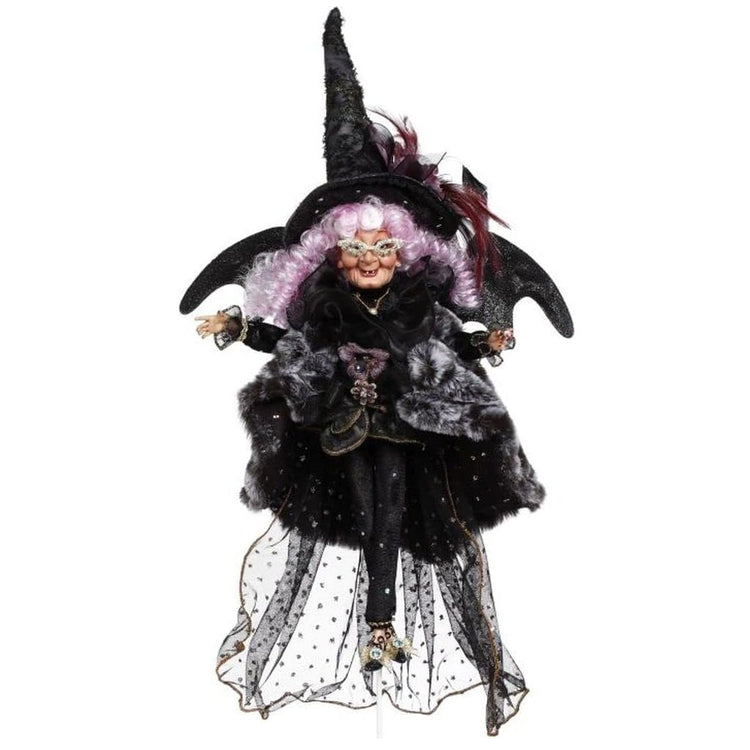 Purple haired witch wearing a black outfit & hat.