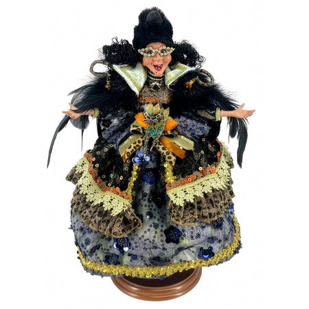 Decorative figurine in an ornate costume with black feathers and sequins on a white background