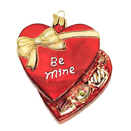 heart shaped ornament like a box of chocolates. Heart is red with gold box and says Be Mine. Box is slightly open showing chocolates