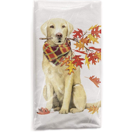 Sitting golden retriever wearing a plaid scarf and holding a small tree branch with leaves in mouth