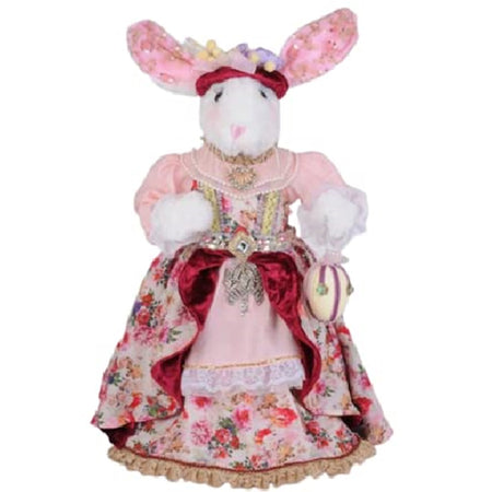 Standing girl bunny figurine in a long dress.  The dressk is pink with roses in pink and reds.  The bunny ears coordinate with the dress patterns. She carries an easter egg.