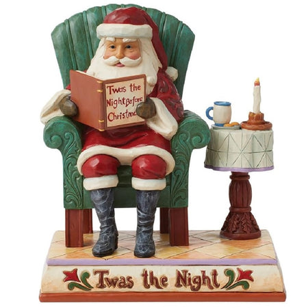 Santa in an armchair reading Twas The Night Before Christmas.
