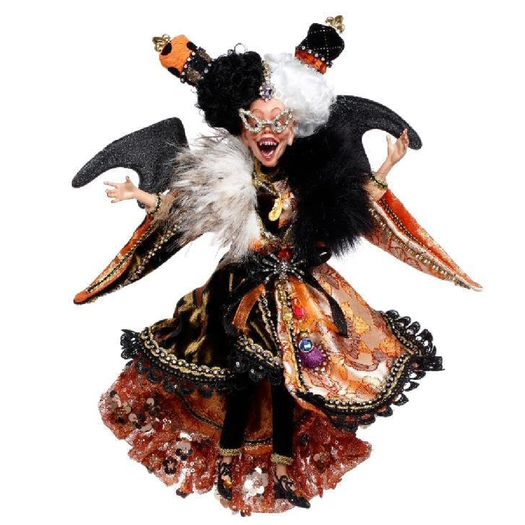 Decorative figurine of a witch with black hair, orange and black dress, and white face on a white background.