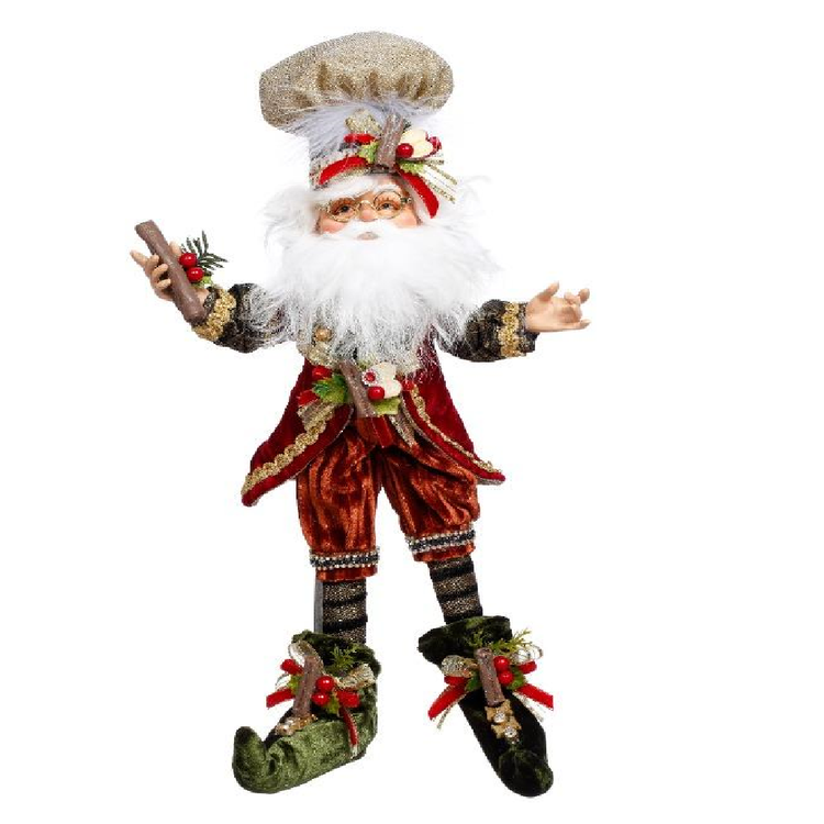 Bearded elf wearing burnt orange suit, hat and suit have apple and cinnamon adornments.