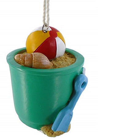 beach bucket shaped hanging ornament. The bucket is green with a blue shovel. The bucket has sand with a shell and beach ball.