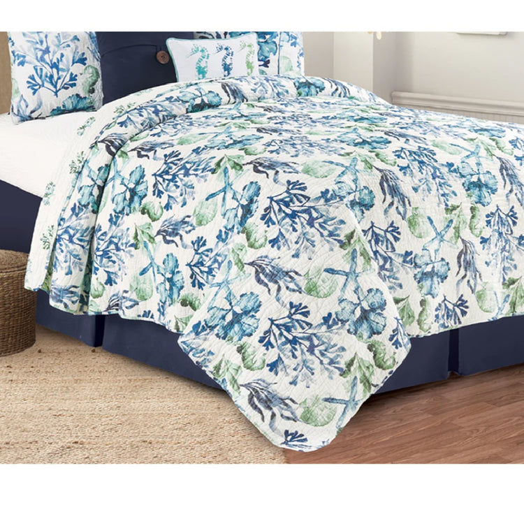 bed with a quilt in blues and greens designed with starfish, sea grass and seahorses