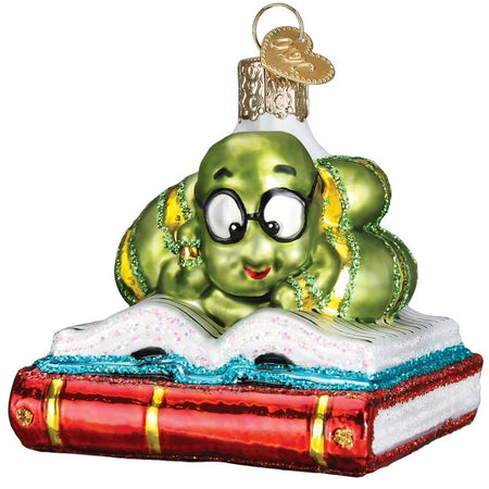 Blown glass ornament of a green "bookworm" reading a blue book stacked on top of a red book. 