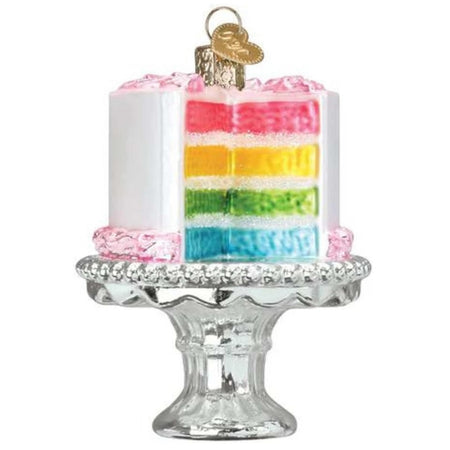 Blown glass ornament depicting a rainbow color layer cake with white icing, sitting on a silver stand.