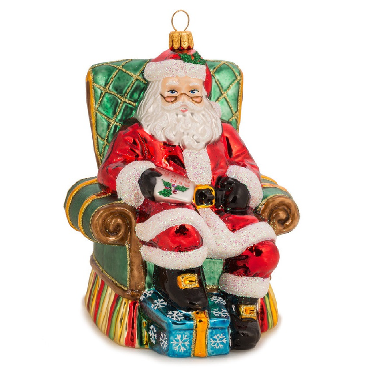 Blown Glass Ornament of Santa sitting in a green arm chair.