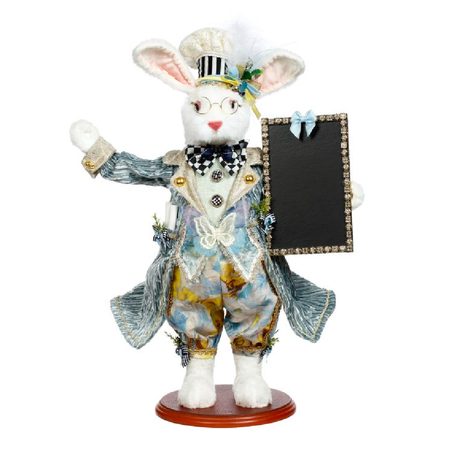 Furry rabbit figurine wearing blue suit, chefs hat, and holding a blank chalkboard sign.