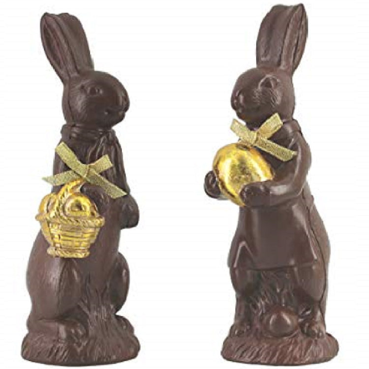 2 figurines made to look like chocolate bunnies. One is holding a gold basket of eggs and one is holding a golden egg, both have gold ribbon bows.