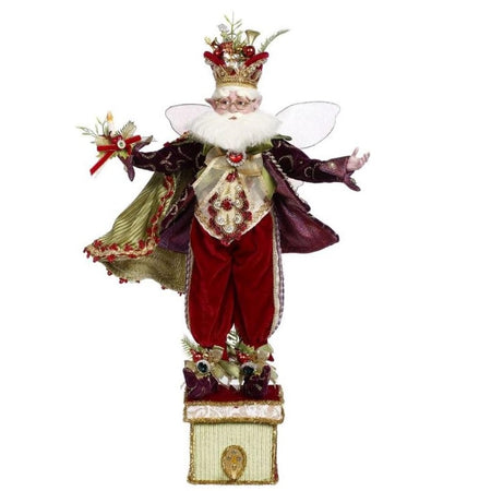 bearded fairy wearing dark red suit and green cape, with crown. Standing on a box with hook for a stocking.