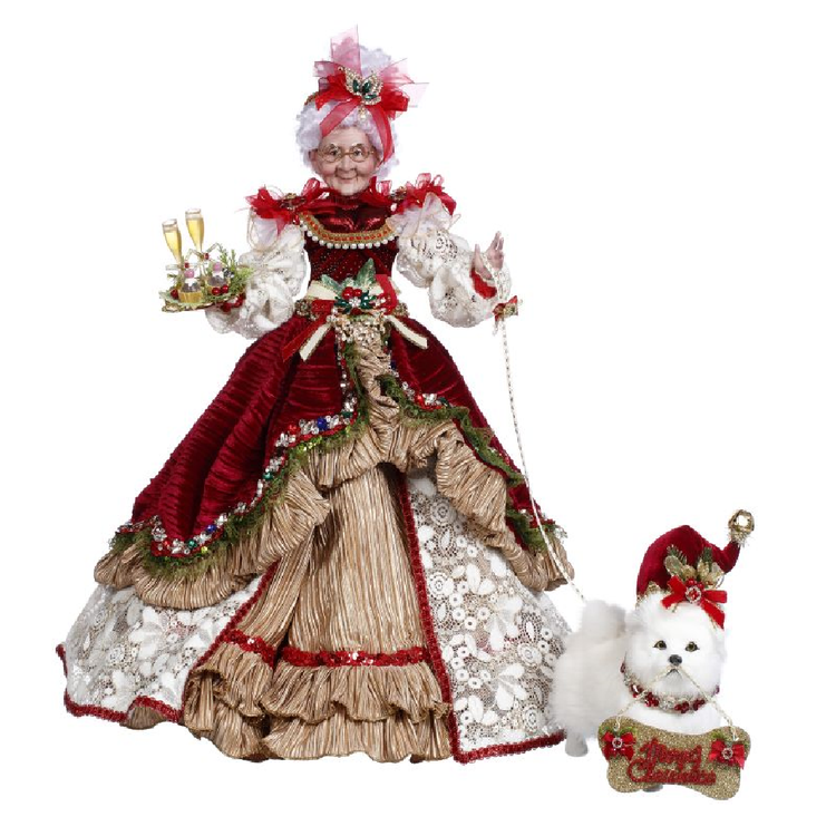 mrs. claus figurine wearing elegant red velvet and lace dress. She's holding a tray of champagne glasses in one hand and the leash of a small white dog in the other. the dog has a sign around its neck that says merry christmas.