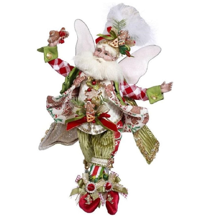 bearded fairy wearing suit made of gingerbread patterned fabric and green velvet. His chefs hat and vest are both adorned with cookies and he's holding a gingerbread cookie in his hand.