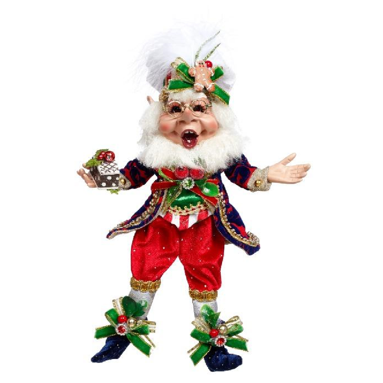 Decorative Christmas elf figurine with red pants, green hat, and holding a gingerbread house on a white background