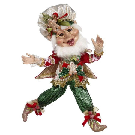 bearded elf wearing gold chefs hat, green pants, and a vest with gingerbread pattern.