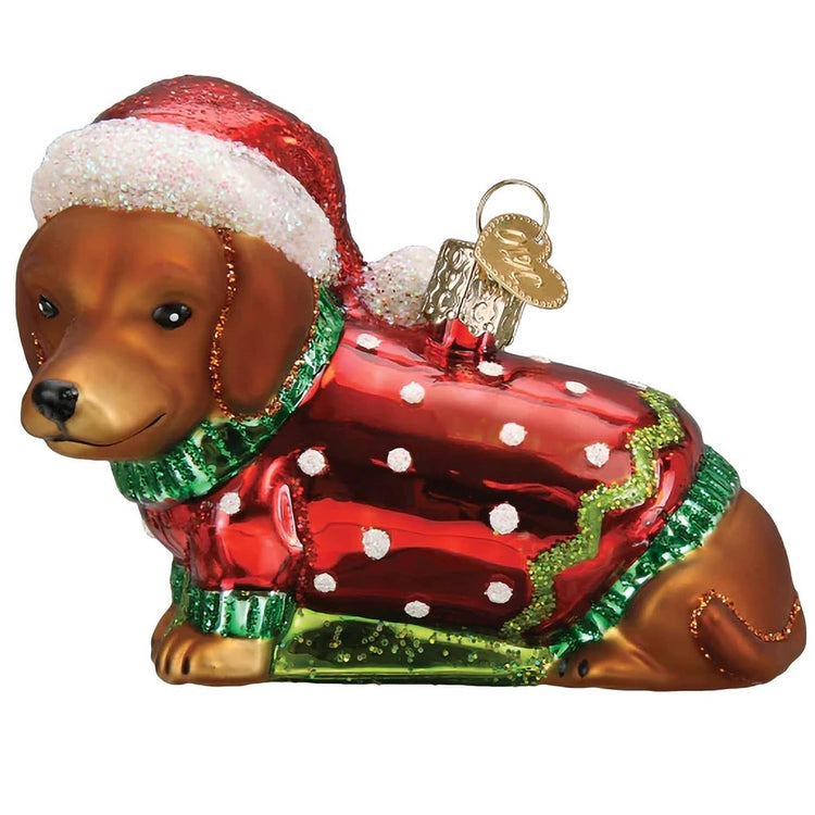 Blown glass ornament of a brown dachshund puppy in a red sweater and santa hat.