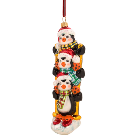 Blown glass ornament of three penguins on top of each other, on some skis.