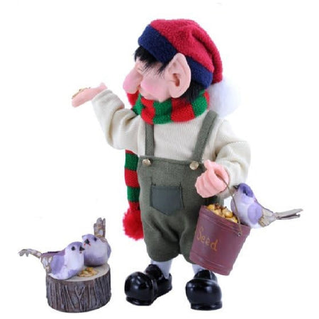 Donatello elf wearing overalls and a red and green scarf, he's holding a bucket of bird seed and feeding 3 little birds.