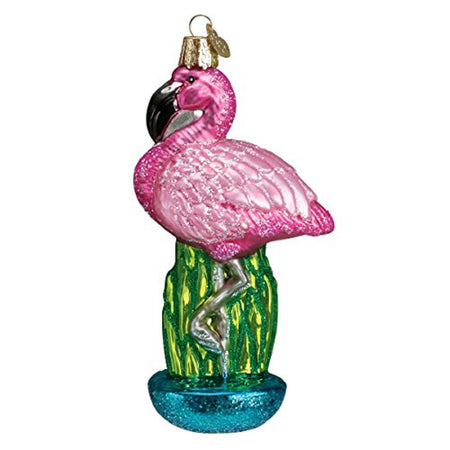 Standing pink flamingo ornament. There is greenery behind his legs and he stands in blue water.