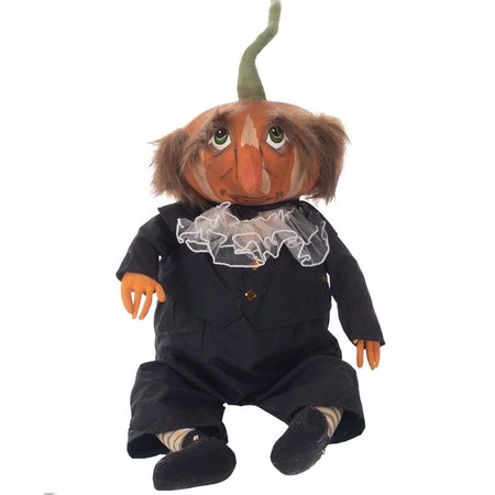 male figurine with a pumpkin for a head. The pumpkin has a long green skin, hair an da painted face with nose. The man is waring a black suit with a white ruffle and black shoes