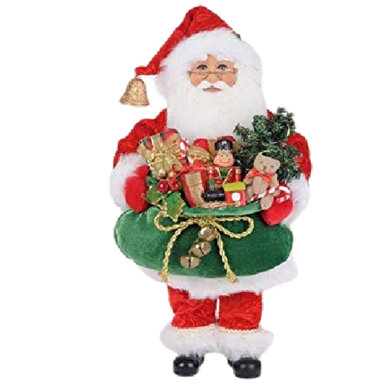 Standing Santa Figurine in traditional closes carrying a full green sack of presents, stuffed bears and nutcrackers with a tree.