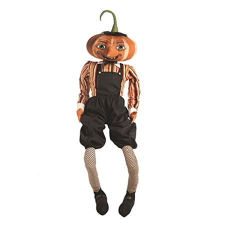 Doll figure with a pumpkin head. He wears zig zag striped socks, booties black overall shorts and a long sleeve striped shirt in fall colors.  Smiling with large eyes.