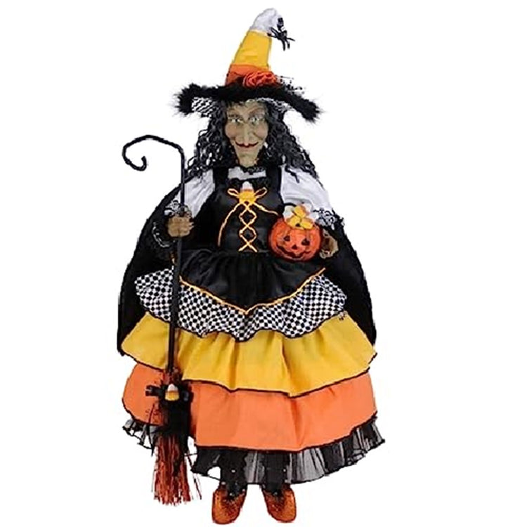 Standing witch figure with long wavy hair. She carries a broom and wears a dress with ruffle layers in orange, yellow, black and black and white checks. Matching hat.  She holds a pumpkin in the other hand.