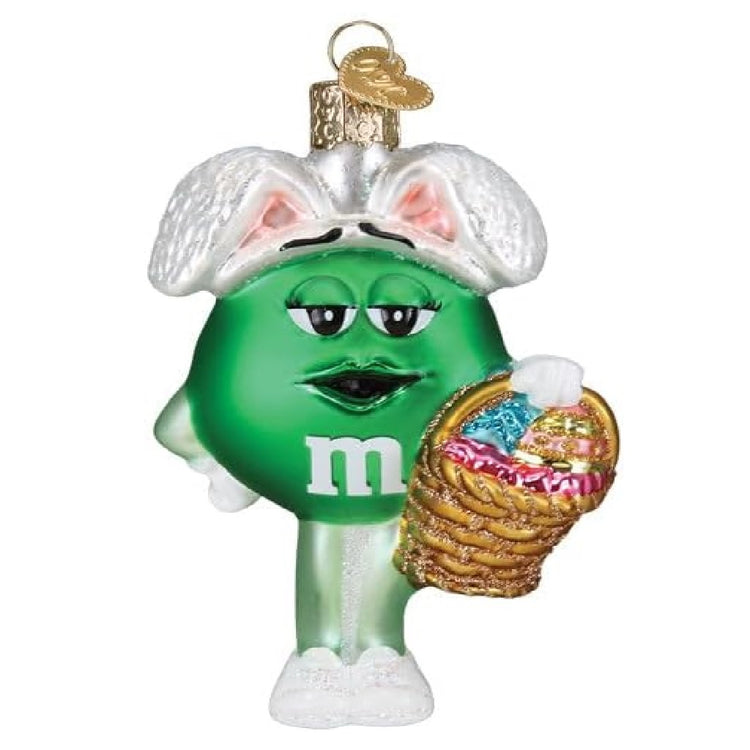 blown glass ornament green m&m wearing bunny ears and holding a basket with easter eggs.