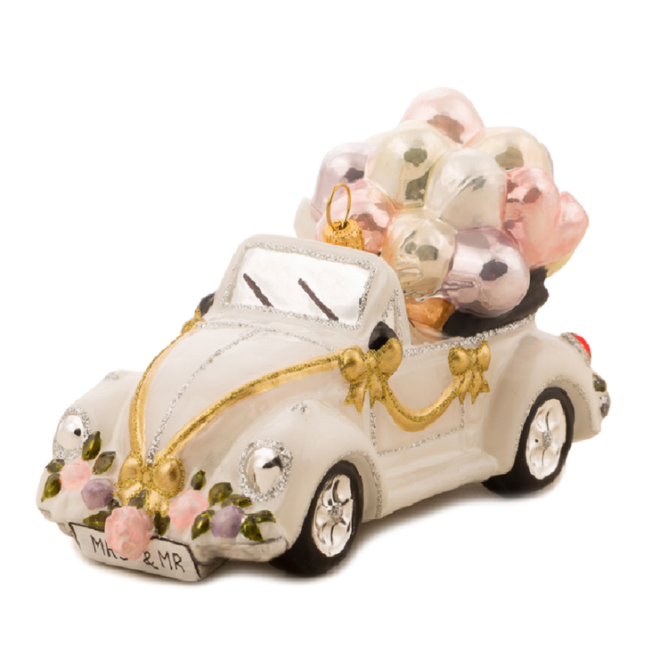 A decorative white convertible car ornament with gold trim, pink flowers, and a bundle of pink and silver balloons on a white background.