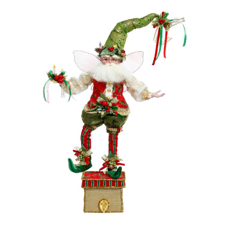 bearded fairy in long green stocking cap and red striped stockings. holding a candle. standing on a gold box with a hook for a stocking.