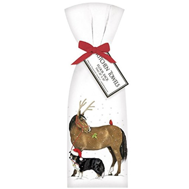 Kitchen towel tied with red ribbon. Shows a horse wearing antlers being led by a black and white dog in a red santa type hat. It is snowing.