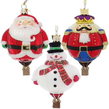 3 blown glass hot air balloon ornaments, one shaped like santa, one is a snowman with red scarf and one is a nutcracker.
