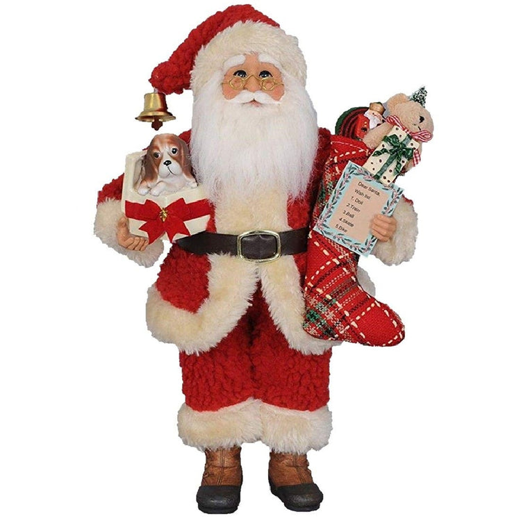 Karen Didion CC12-25 Christmas Surprise Santa 12.5-inch collectible figurine holding a puppy in a gift box and carrying a festive toy-filled stocking.