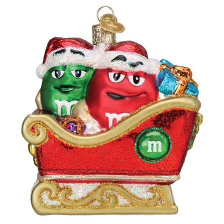 Red holiday sleigh with gold trim.  Sitting in the sleigh are 2 M&M candies, one green and one red with santa hats and gifts.