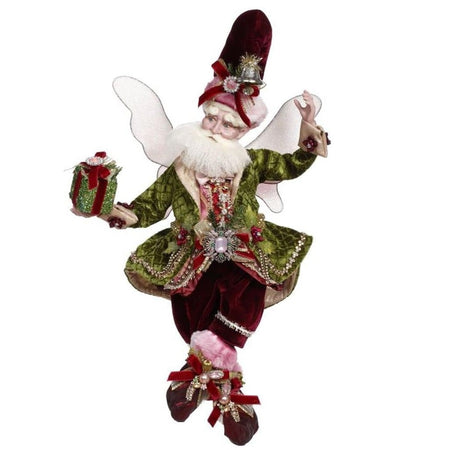 bearded fairy in dark red velvet pants and hat, a green velvet jacket, and holding a wrapped present.