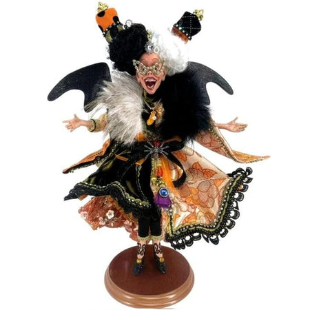 Decorative figurine of a witch with black and white hair, orange and black dress