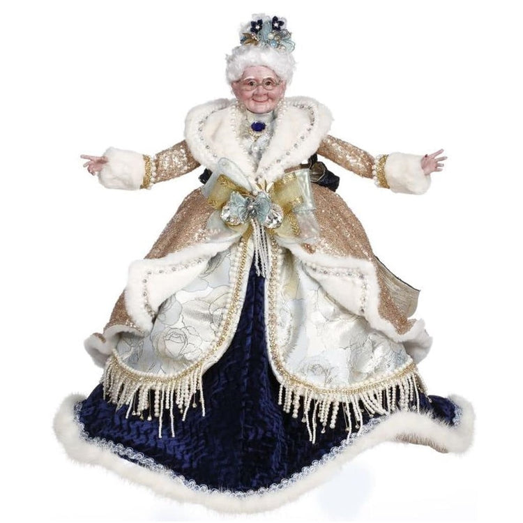 Mrs. Claus wearing dark blue velvet dress, with silver and gold bead overskirt, and a gold glittery jacket trimmed with white fur.