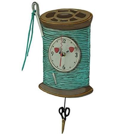 clock shaped like a spool of thread with a needle tucked inside. Thread is teal color with sissors for a pendulum