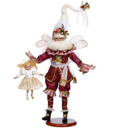 bearded fairy wearing pinnk and red, a white stocking cap, and holding a ballerina doll.