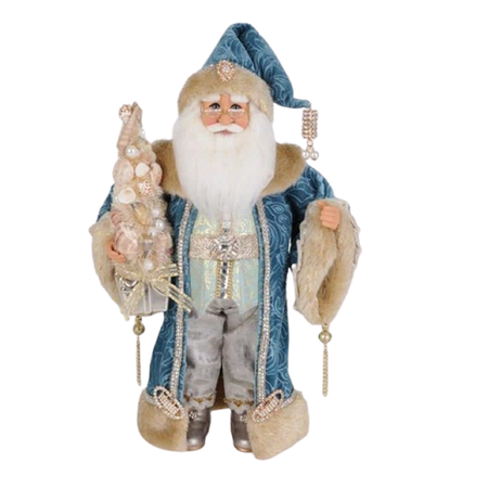 Santa in dark blue long coat and matching hat, bordered in rhinestones and tan fur. He's holding a small tree made of shells.