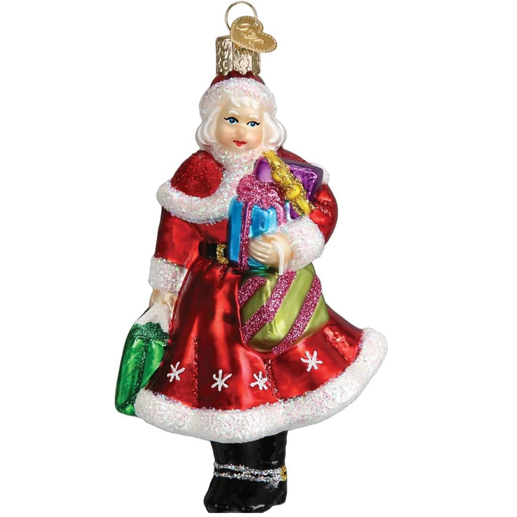 Mrs. Claus shaped hanging ornament. She is wearing the traditional red dress with matching cape both trimmed in glass white fur. She is carrying gifts