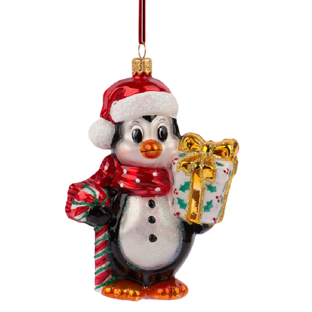 Blown glass ornament of a penguin in hat and scarf, holding a gift, and a candycane.