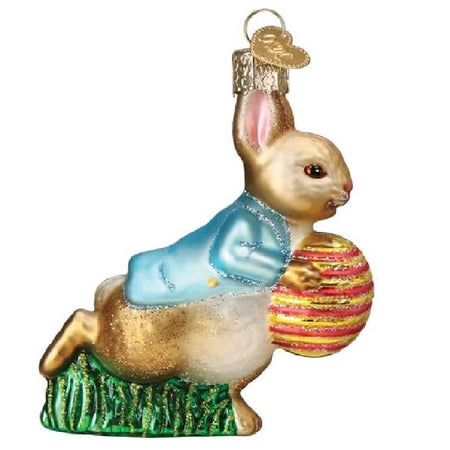 blown glass ornament depicting peter rabbit in his blue coat, holding a striped easter egg while running.