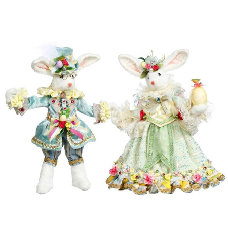 two fluffy white rabbit figurines, one in a blue suit and top hat, and the other in a light yellow gown with flower accents.