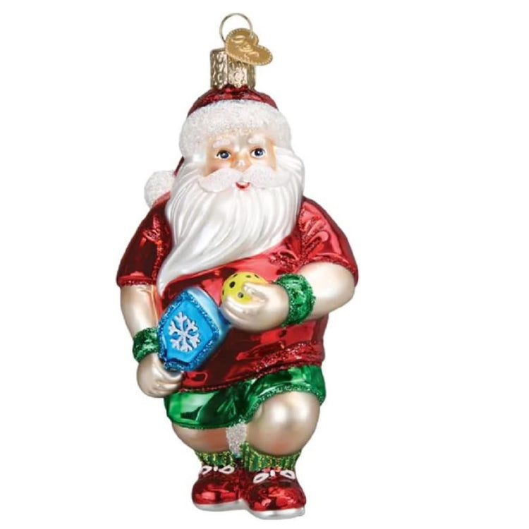 Blown glass Santa ornament, Santa is in a red shirt and green shorts, holding a pickleball and a pickleball paddle.