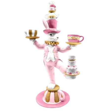 White rabbit in a pink suit and top hat, he's standing on an oversize teacup, balancing two in his hands, a cake on one foot and a stack of teacups and a teapot on his hat.