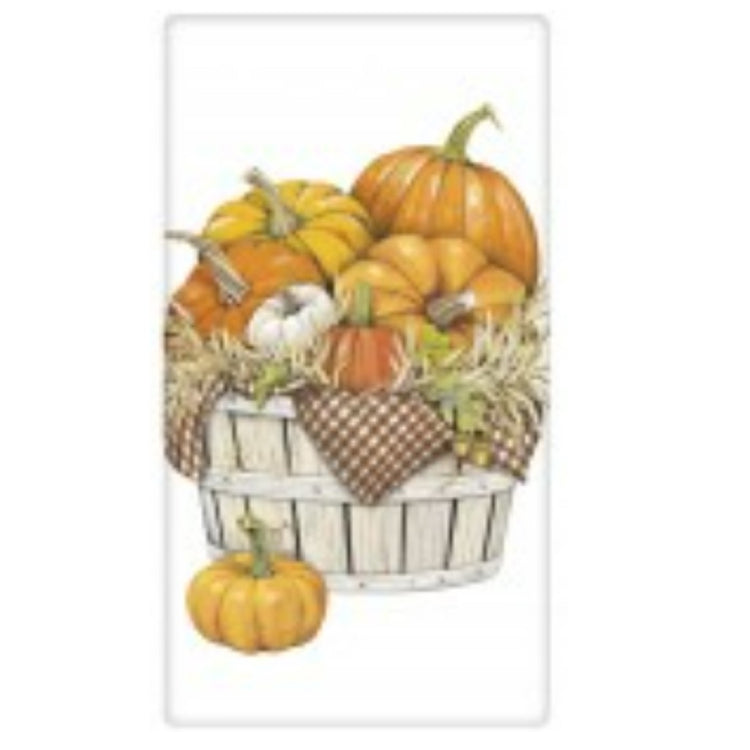 Light colored wooden basket lined with red and white checkered cloth and stuffed with pumpkins. One pumpkin sitting beside the basket.