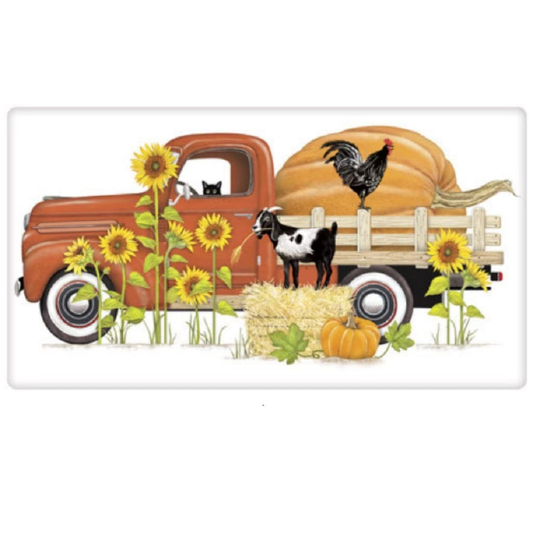 White kitchen towel with an orange pickup truck, black cat looking out of the drivers window.  Giant pumpkin in bed of truck wiith a black rooster on the edge of truck.  Goat on a bale of hay in front of the side view of truck.  Sunflowers growing.
