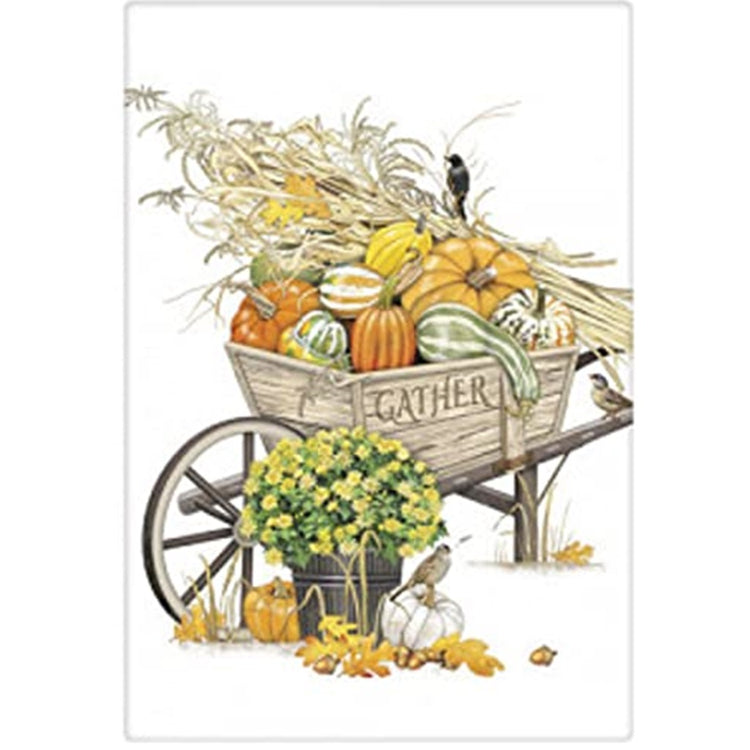 folded white kitchen towel with a wheelbarrow full of pumpkins and wheat stalks.